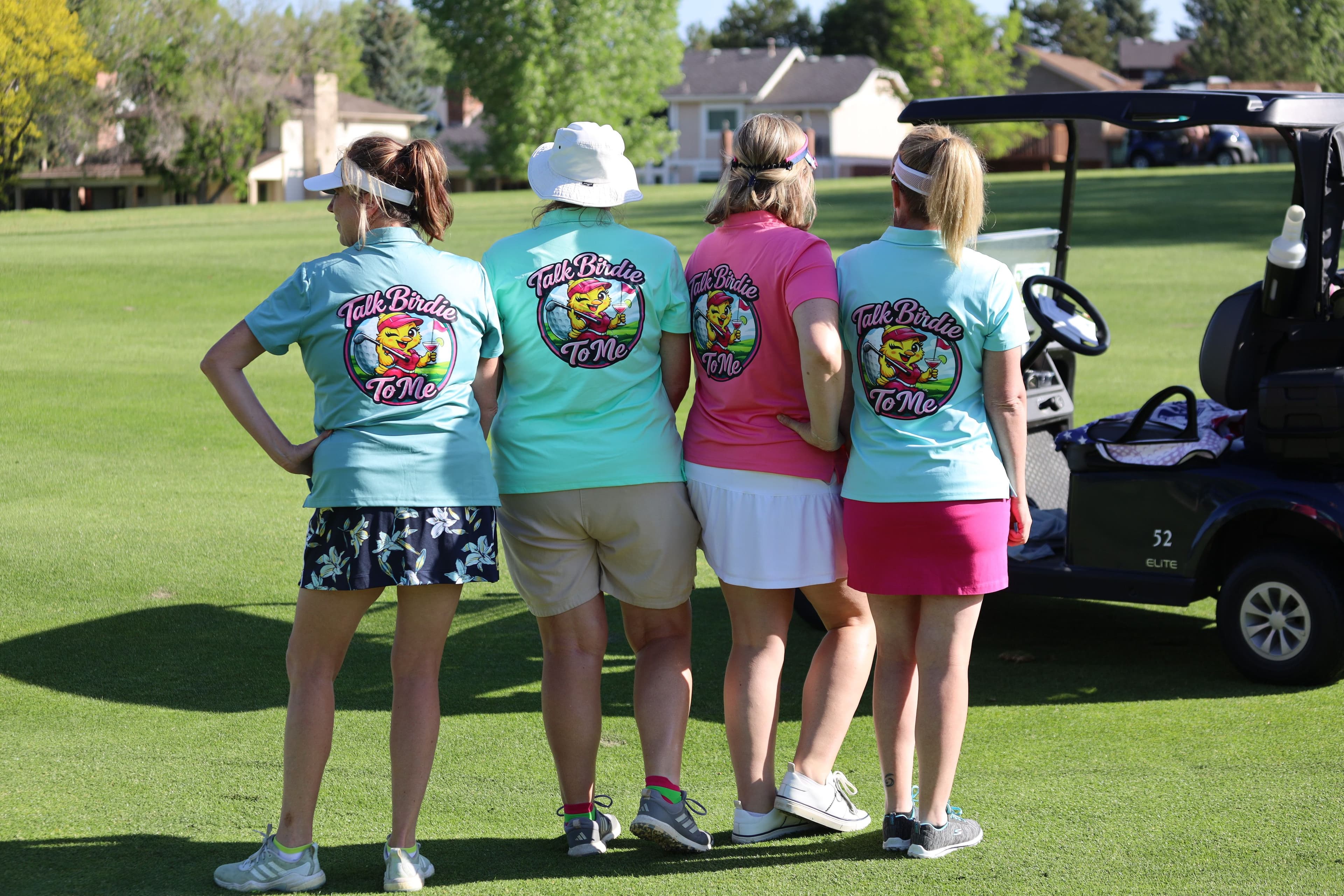 Four golfers stand side-by-side on the course wearing custom "Talk Birdie To Me" team shirts.